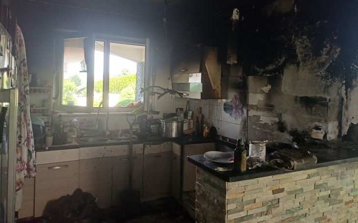 Klatka i kuchnia po pożarze z widokiem na zniszczone ściany i sprzęty.