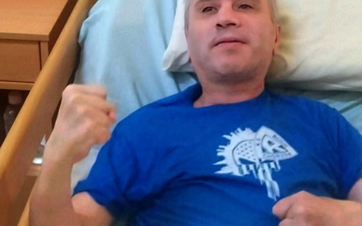 Mężczyzna w niebieskiej koszulce leżący na łóżku.