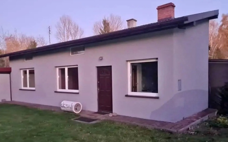 Nowoczesny dom z szarym tynkiem i dużymi oknami.