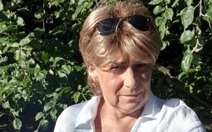 Kobieta w okularach przeciwsłonecznych na tle zieleni.