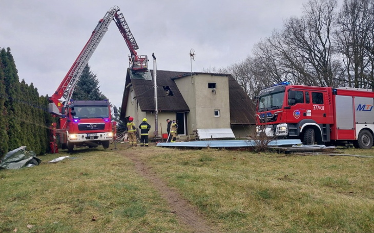 Strażacy pracujący przy usuwaniu skutków pożaru budynku.