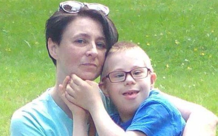 Matka z dzieckiem na tle zielonej trawy, wyraz miłości i bliskości.