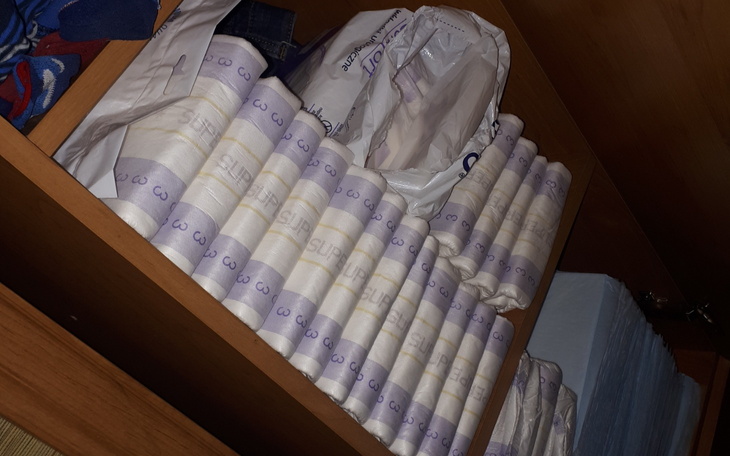 Półka z złożonymi ręcznikami i torbą, w drewnianym wnętrzu.