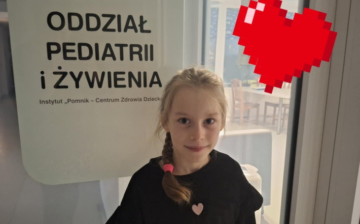 Dziewczynka w szpitalu, uśmiechnięta z sercem w tle.