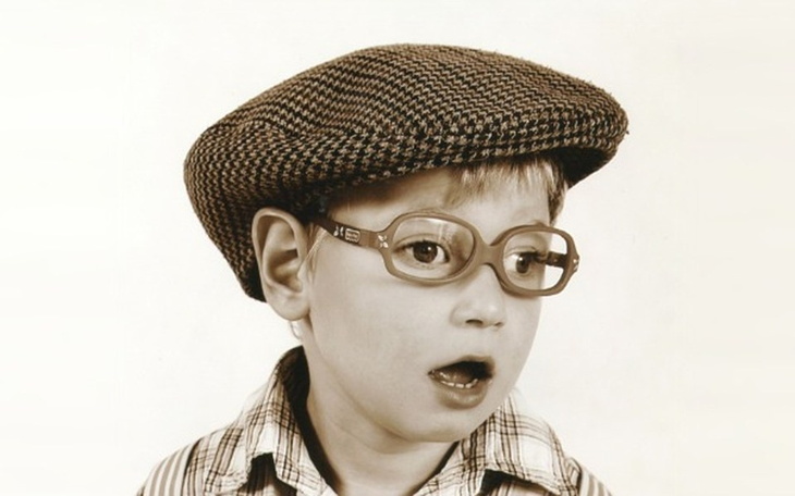 Chłopiec w kapeluszu i okularach, zaskoczony wyrazem twarzy.