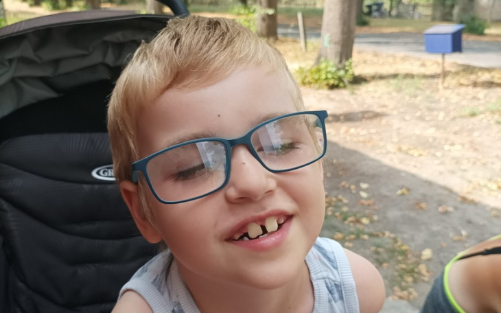 Chłopiec w okularach, uśmiechający się do kamery.