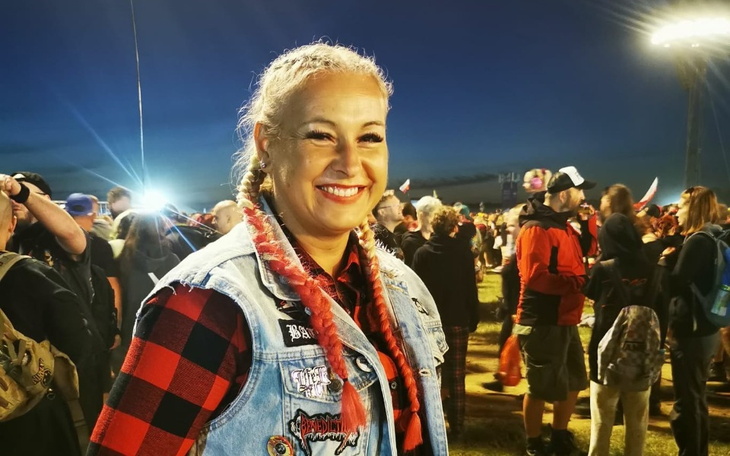 Uśmiechnięta kobieta w tłumie na festiwalu, w stylu rockowym.