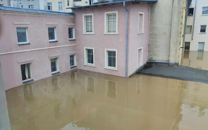 Zalane podwórko z różowym budynkiem w tle.