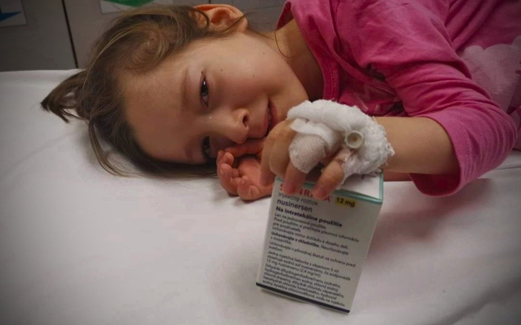 Dziewczynka leży w szpitalu, trzymając lek w ręku.