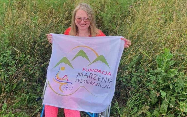 Kobieta trzymająca flagę Fundacji Marzenia bez Ograniczeń.