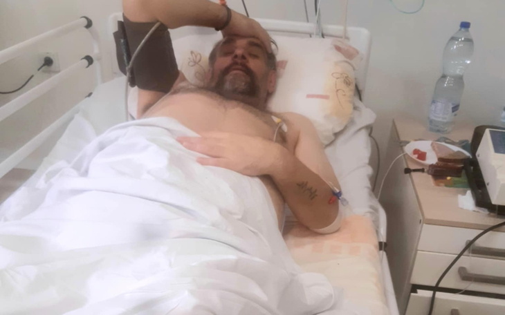 Mężczyzna leżący w szpitalnym łóżku, zmartwiony.