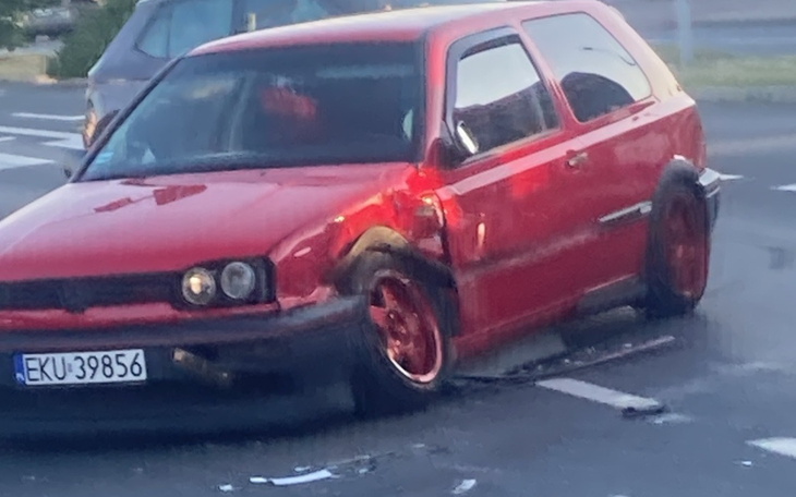 Uszkodzony czerwony samochód na parkingu.