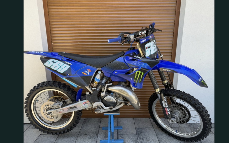 Motocykl terenowy w niebieskim kolorze, stojący na podstawce.