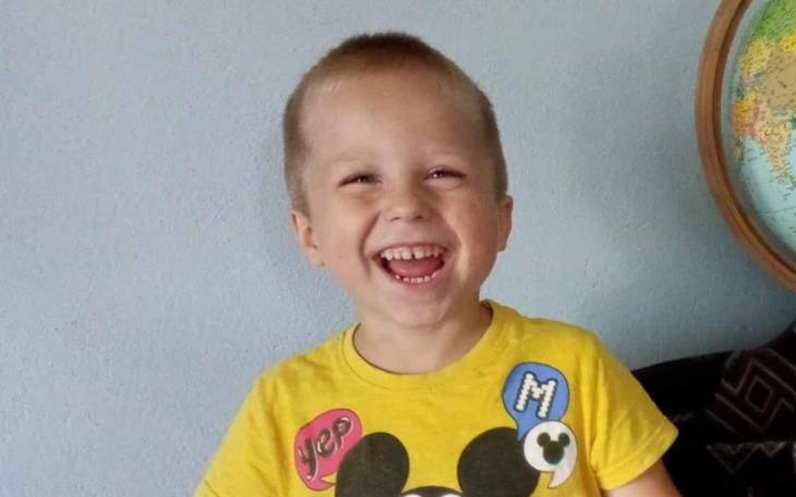 Chłopiec w żółtej koszulce, szeroko się uśmiecha.