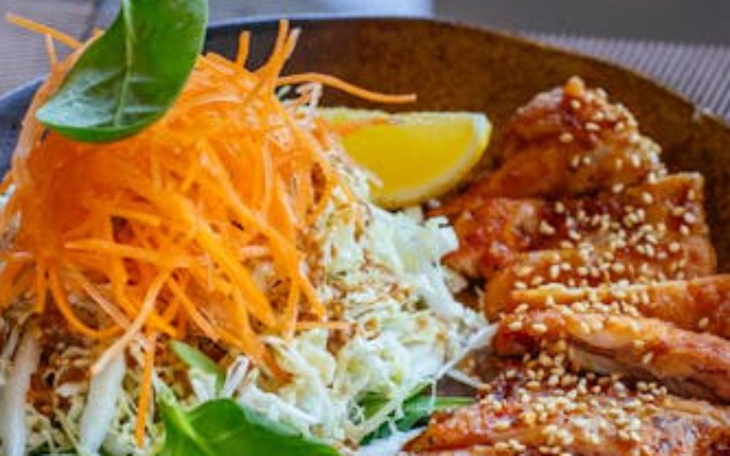 Talerz z sałatką i kawałkami kurczaka, udekorowany marchewką.