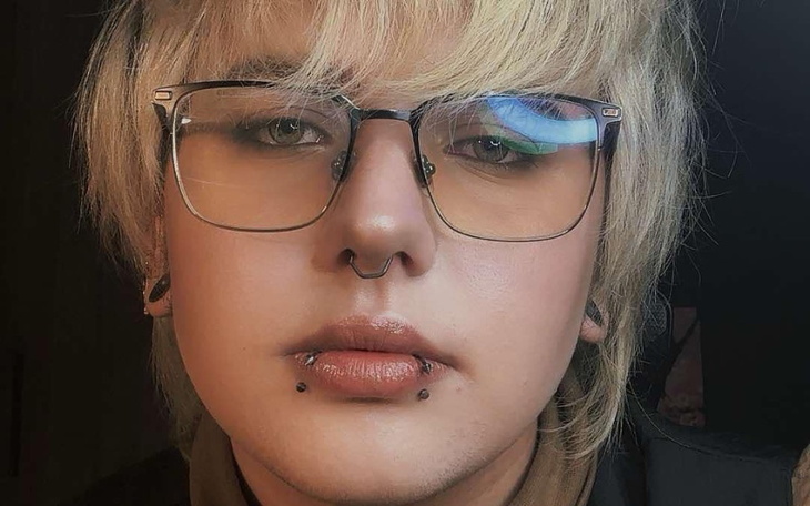 Osoba z jasnymi włosami i okularami, patrząca w obiektyw.