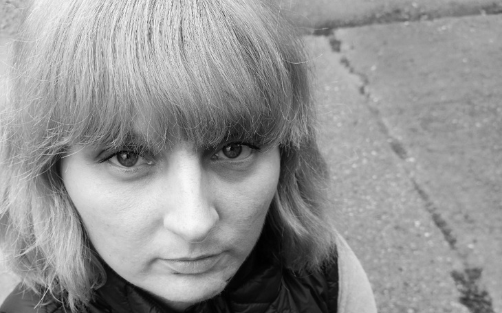 Kobieta z krótkimi włosami, patrząca w obiektyw, w czarno-białym ujęciu.