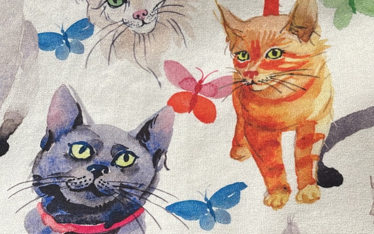 Ilustracja kotów z motylami na tkaninie.