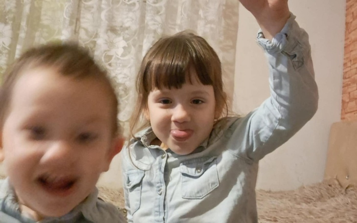 Dzieci bawiące się w domu, jedna z nich pokazuje język.