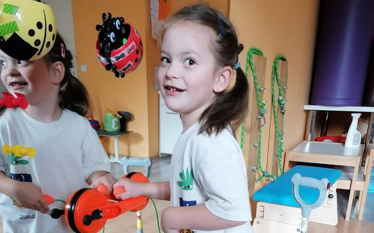 Mała dziewczynka bawiąca się zabawkami w przedszkolu, uśmiechnięta.