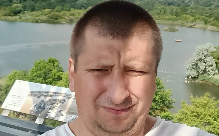 Mężczyzna na tle rzeki, z wyraźnym zmartwieniem na twarzy.