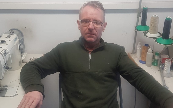 Mężczyzna siedzący przy maszynie do szycia w warsztacie.