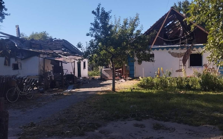 Zniszczony budynek z uszkodzonym dachem i zarośniętym terenem.