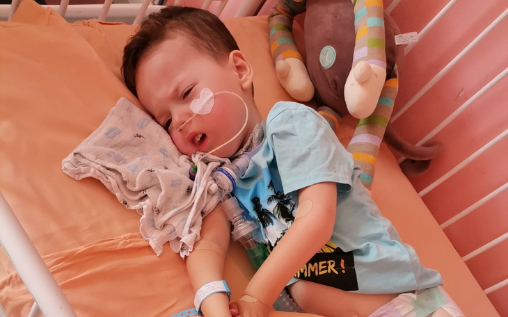 Chłopiec w łóżku szpitalnym, z rurkami i smutną miną.