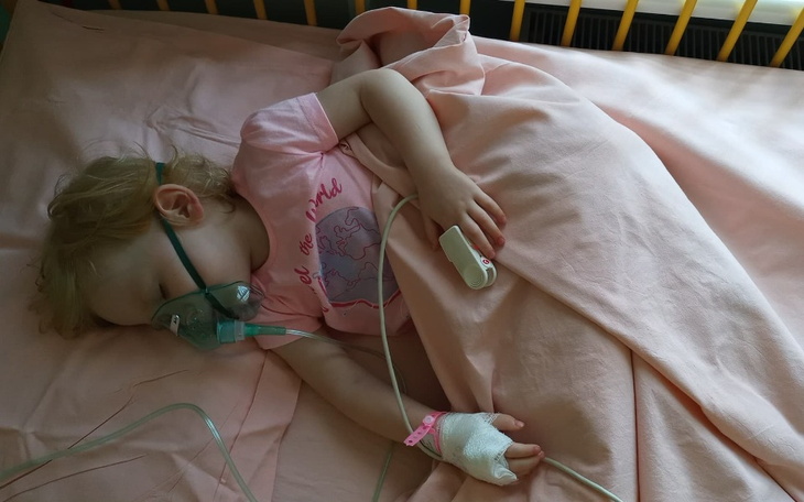 Mała dziewczynka w szpitalu, śpi z maską tlenową.