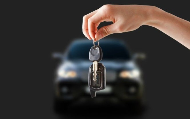 Ręka trzymająca kluczyki do samochodu na tle pojazdu.