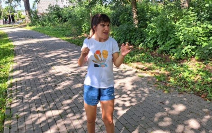 Kobieta w t-shircie, rozmawiająca na ścieżce w parku.