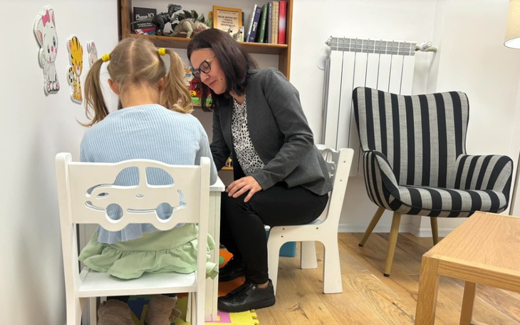 Dziecko bawi się z terapeutą w przytulnym pomieszczeniu.
