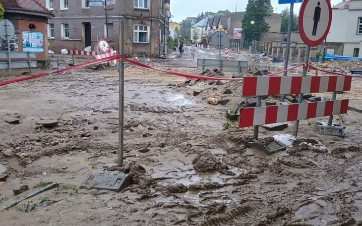 Zniszczona ulica po ulewie, z przeszkodami drogowymi.
