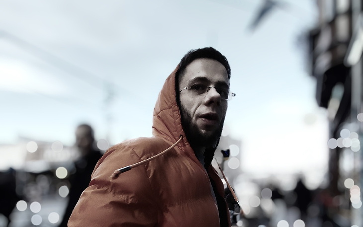 Mężczyzna w pomarańczowej kurtce na ulicy.