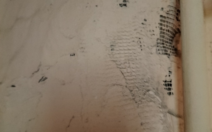 Fragment ściany z widocznymi uszkodzeniami i zarysowaniami.