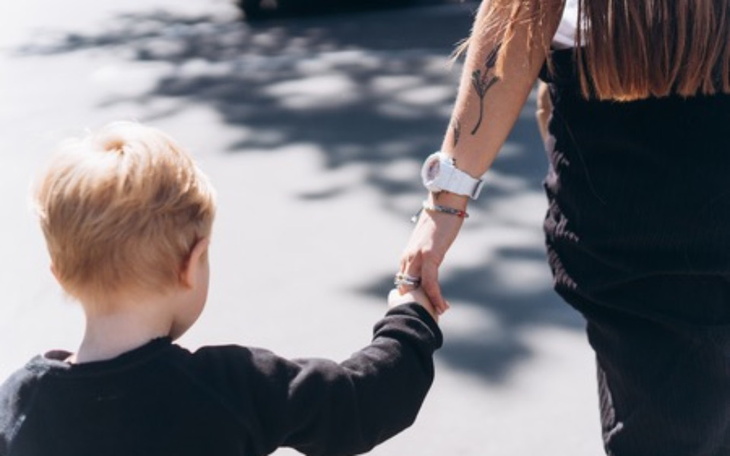 Dziecko trzymające się za rękę z dorosłym.