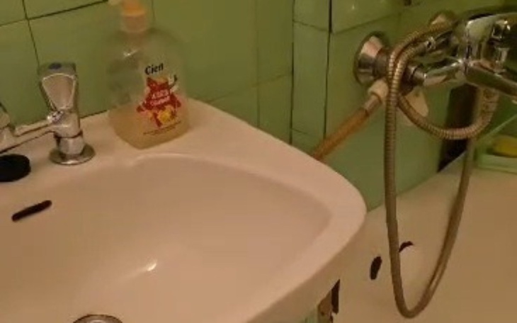 Widok na umywalkę w łazience z zielonymi kafelkami.