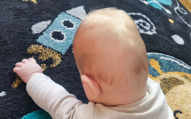 Małe dziecko bawi się na kolorowym dywanie.