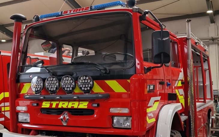 Przystojny strażacki wóz w hali strażniczej, błysk czerwieni i żółte odblaski.