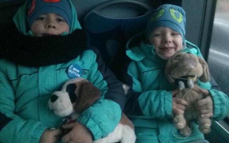Dzieci w zimowych kurtkach z pluszakami w autobusie.