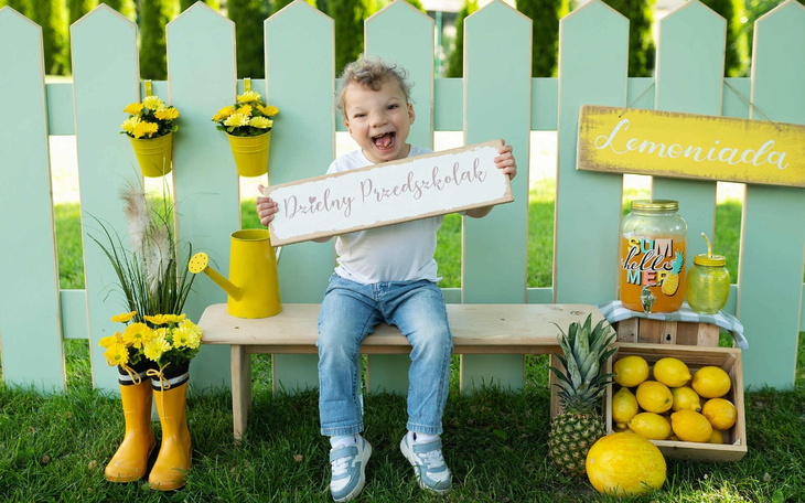 Chłopiec trzymający tabliczkę z napisem 'Dzielny Przedszkolak'.