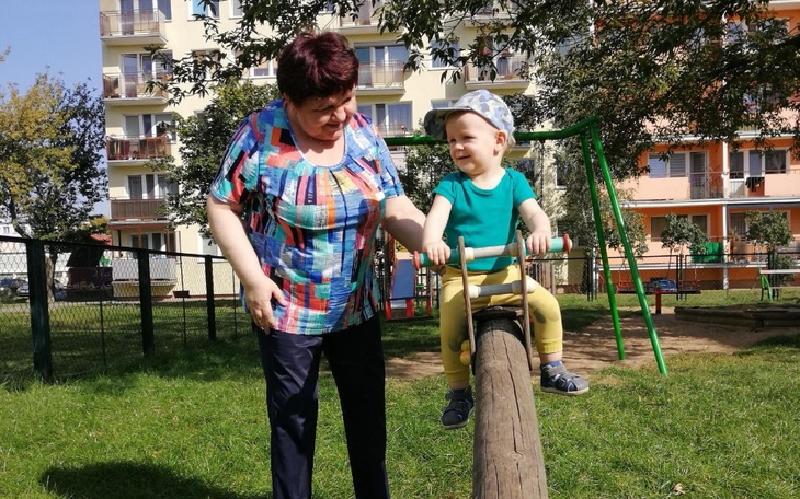 Dziecko bawi się na huśtawce z uśmiechniętą osobą dorosłą.