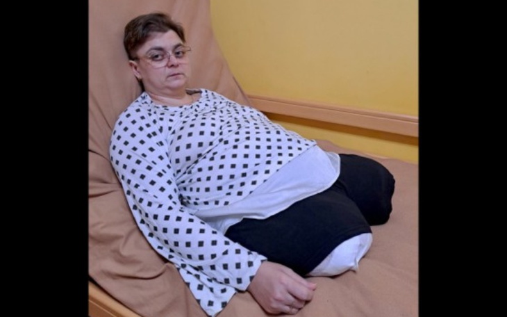 Kobieta siedzi na łóżku, wygląda na zmartwioną.