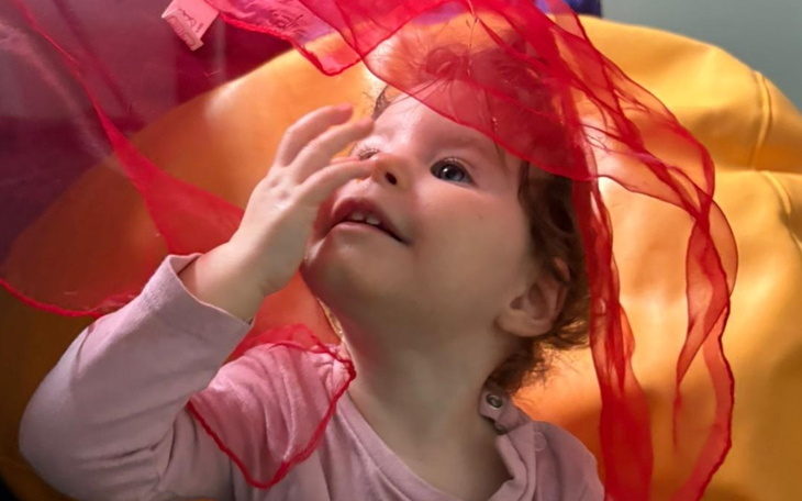 Mała dziewczynka bawiąca się czerwonymi chustkami.