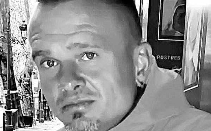 Człowiek w czarno-białym ujęciu, z wyrazem powagi na twarzy.