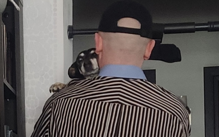 Mężczyzna z psem na ramieniu, widok z tyłu.