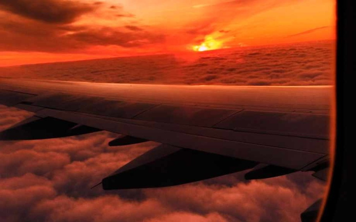 Widok z okna samolotu na zachód słońca nad chmurami.