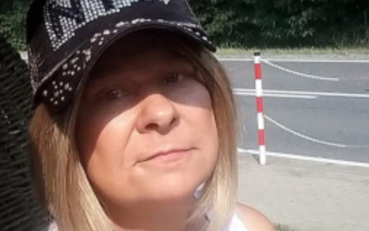Kobieta w czapce, siedząca na zewnątrz, z poważnym wyrazem twarzy.
