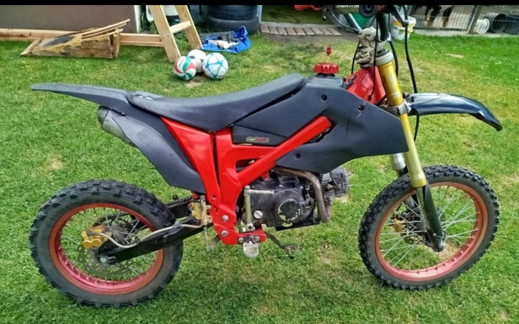 Motocykl terenowy na trawie, gotowy do jazdy.