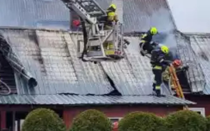 Strażacy gaszący pożar na dachu budynku.